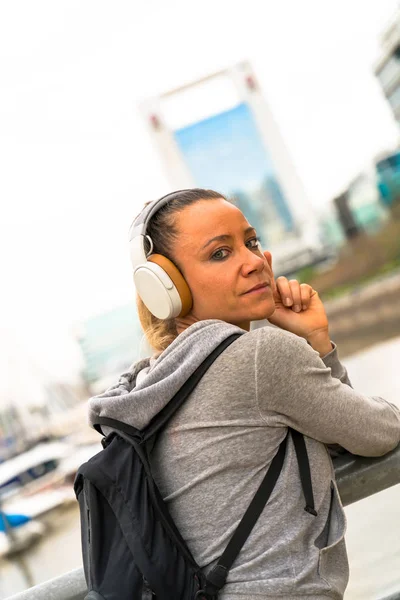 Una donna atletica che ascolta musica vicino alla ringhiera del ponte — Foto Stock