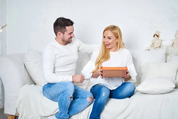 Casal em um sofá dando presentes — Fotografia de Stock