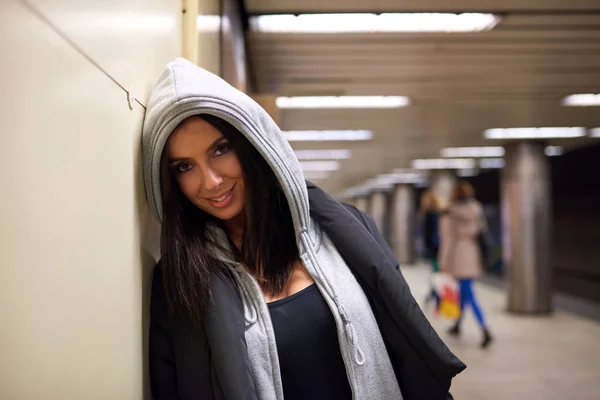 Een lachende jonge vrouw zich bij een metrostation — Stockfoto