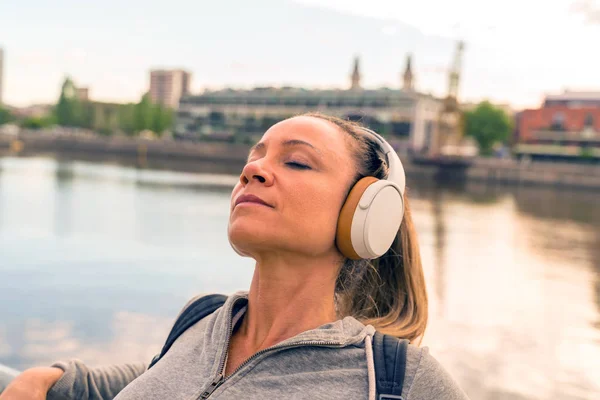 Una donna atletica che ascolta musica vicino alla ringhiera del ponte — Foto Stock