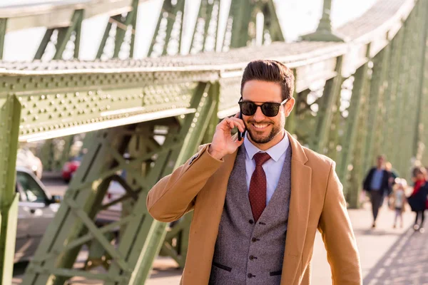 Un uomo elegante in piedi su un ponte e che parla al telefono — Foto Stock