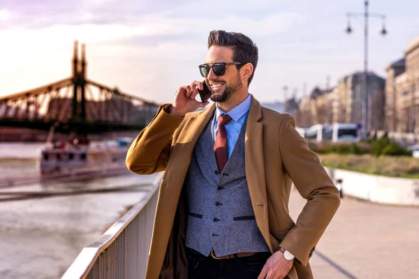 Un hombre elegante al lado de un río hablando por teléfono — Foto de Stock