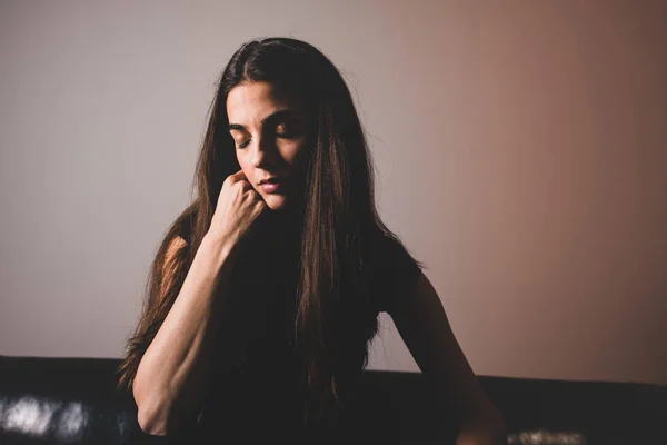 A serious young woman sitting on a sofa — Stock Photo, Image