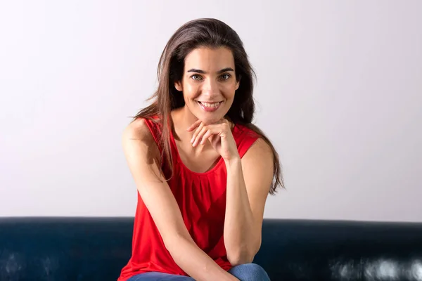 Een glimlachende jonge vrouw zittend op een bank — Stockfoto