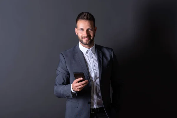 Ένας χαμογελαστός επιχειρηματίας χρησιμοποιεί το smartphone του — Φωτογραφία Αρχείου