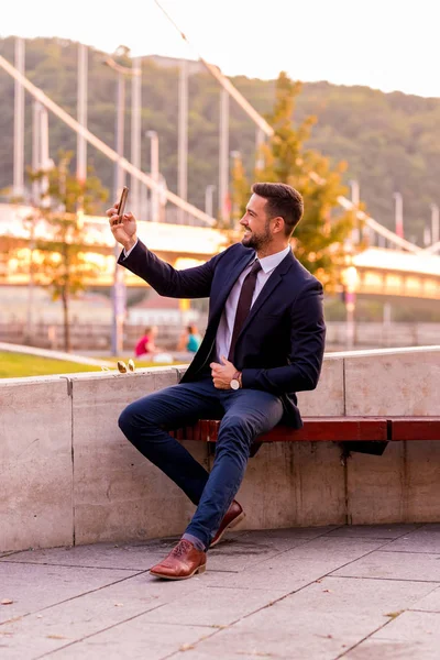 Un uomo d'affari seduto su una panchina a farsi un selfie — Foto Stock