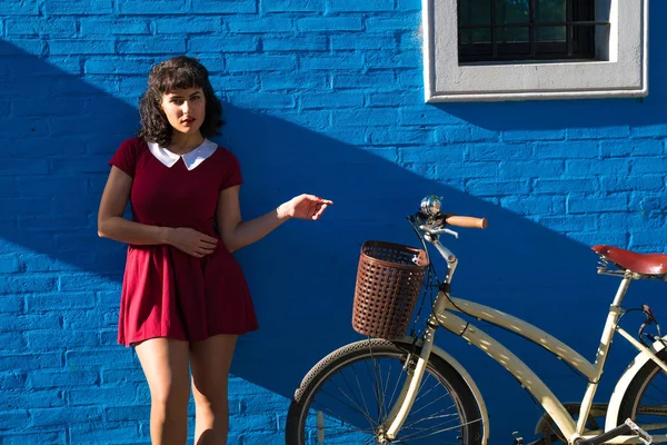 A woman with a bike posing in front of a brick wall — Stock Photo, Image