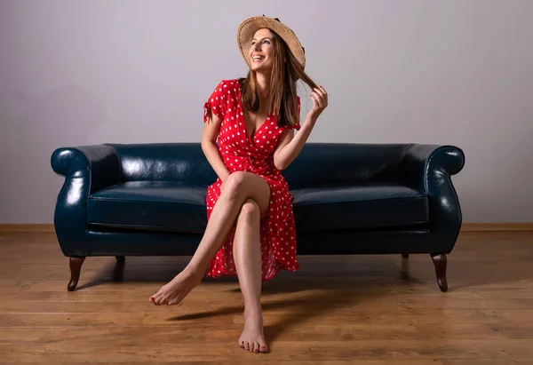 Uma mulher em um vestido vermelho sentado em um sofá — Fotografia de Stock