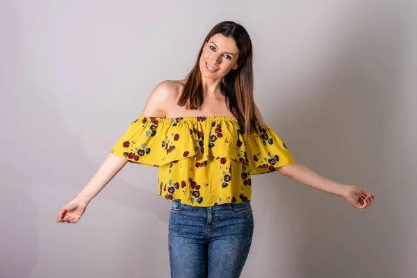 En lycklig kvinna i gul klänning som står i en studio — Stockfoto