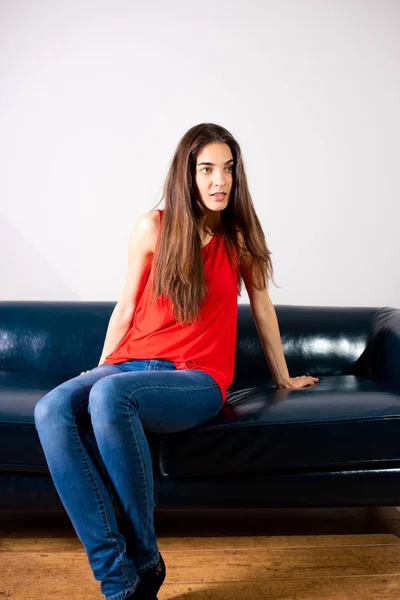 Une jeune femme souriante assise sur un canapé — Photo