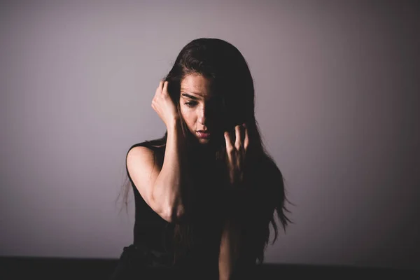 Een serieuze jonge vrouw zittend op een bank — Stockfoto