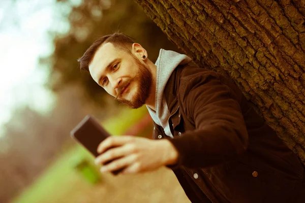 Retro style photo of a hipster man taking a selfie in the park — Stock Photo, Image