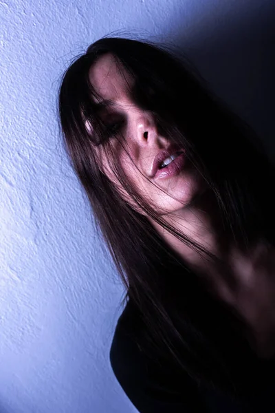 Dark mood portrait of a woman in front of a wall — Stock Photo, Image