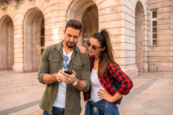 Una pareja tratando de obtener orientación utilizando un mapa en su teléfono móvil —  Fotos de Stock