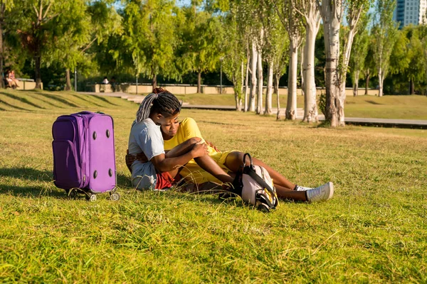 Молодая пара с багажом отдыхает в парке — стоковое фото