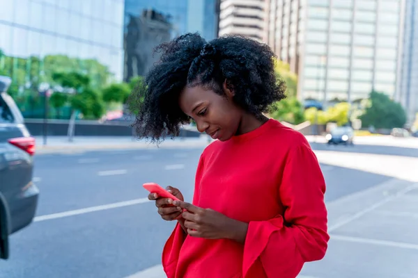 Uma bela mulher negra usando seu telefone em uma cidade grande — Fotografia de Stock