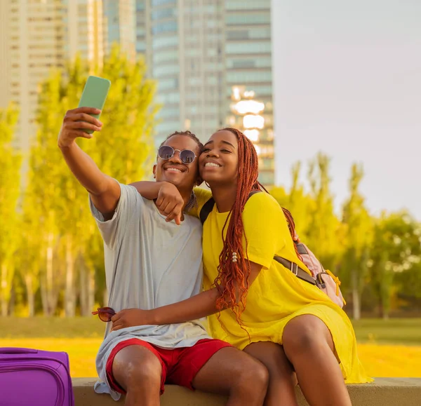 Ett resande svart par som tar selfies i en park — Stockfoto