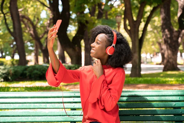 Een vrouw die naar muziek luistert op haar koptelefoon in een park — Stockfoto