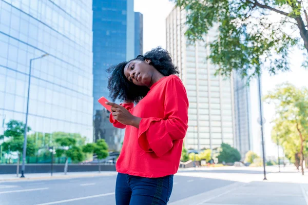 Uma bela mulher negra usando seu telefone em uma cidade grande — Fotografia de Stock