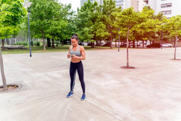En atletisk kvinna som använder sin smartphone i parken — Stockfoto