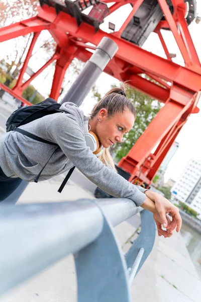 En atletisk kvinna vilar och lutar sig mot bron räcke — Stockfoto