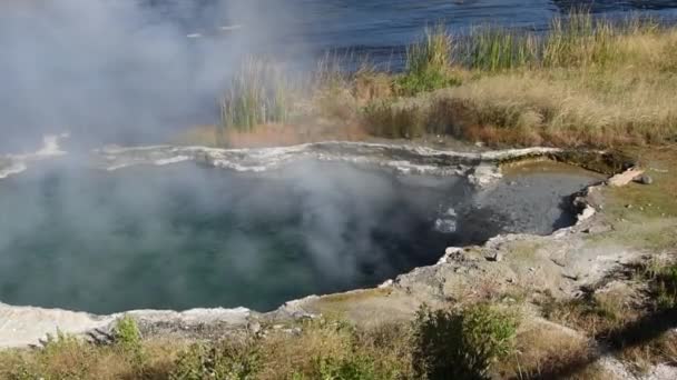 黄石国家公园的一个温泉流入火孔河 相机是手持式的 倾斜着显示火孔河 — 图库视频影像