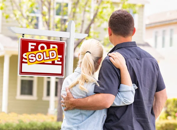 白人夫妇面对出售的房地产标志和房子前 — 图库照片