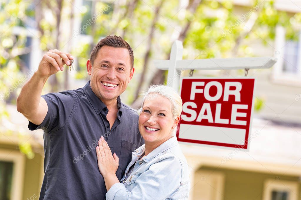 Caucasian Couple in Front of For Sale Real Estate Sign and House with Keys.