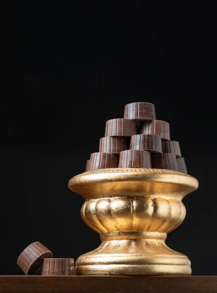暗い背景と黄金柱料理に高級チョコレートのスタック — ストック写真