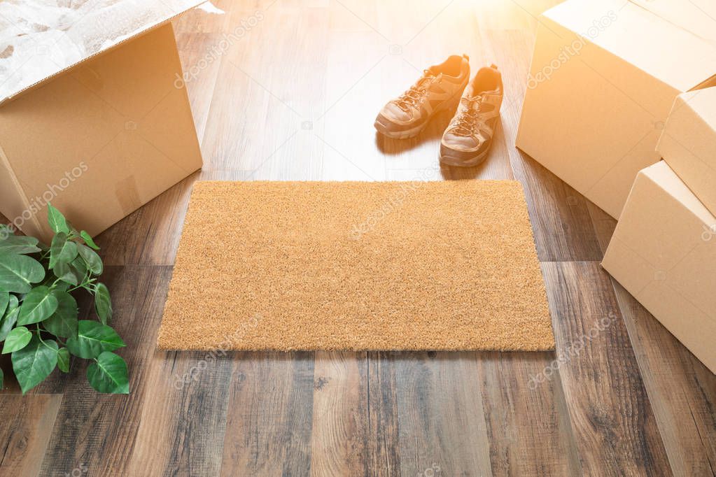 Blank Welcome Mat, Moving Boxes, Shoes and Plant on Hard Wood Floors.