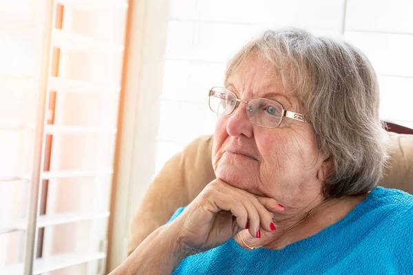 Kontemplativa Senior Kvinna Blickar Genom Hennes Fönster — Stockfoto