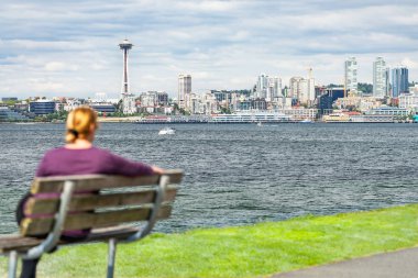 Woman Sitting on Bench Looking At The Seattle, Washington Skyline clipart