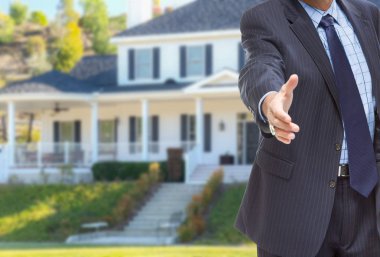 Male Agent Reaching for Hand Shake in Front of Beautiful New House. clipart