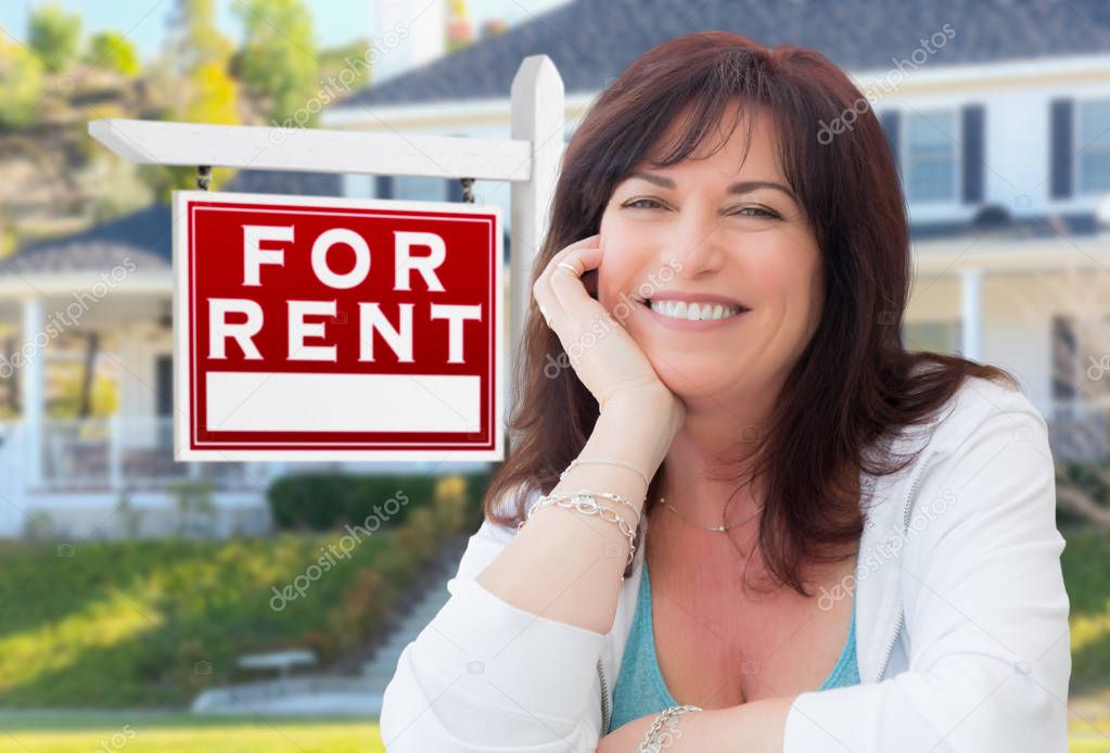 Middle Aged Woman In Front of House with For Rent Real Estate Sign In Yard.