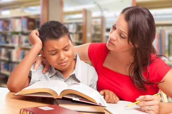 不安的西班牙裔年轻男孩和 Famle 成人在图书馆学习 — 图库照片