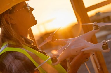 Kadın insansız uçak sistemi (Uas) Quadcopter uçak Pilot Holding dron inşaat sahasında.