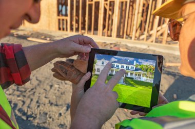 Erkek ve dişi inşaatı işçi ev bilgisayar defterinde inşaatı sitesinde gözden geçirme.