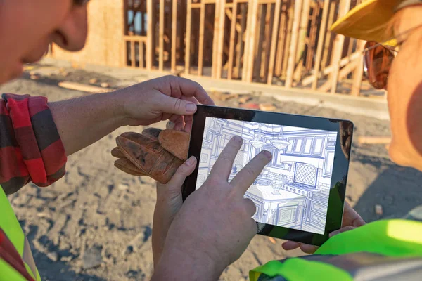 Male and Female Construciton Workers Reviewing Kitchen Drawing on Computer Pad at Construciton Site.