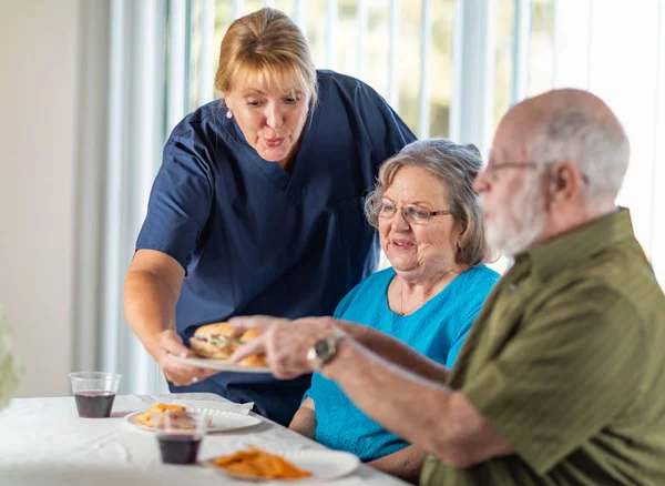 Female Doctor Nurse Serving Senior Adult Couple Sandwiches Table — Stock Photo, Image