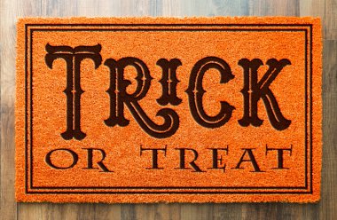 Trick Or Treat Halloween Orange Welcome Mat On Wood Floor Background. clipart