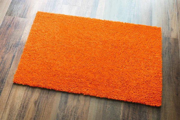 空白橙色欢迎垫在木地板背景准备好你自己的文本 — 图库照片