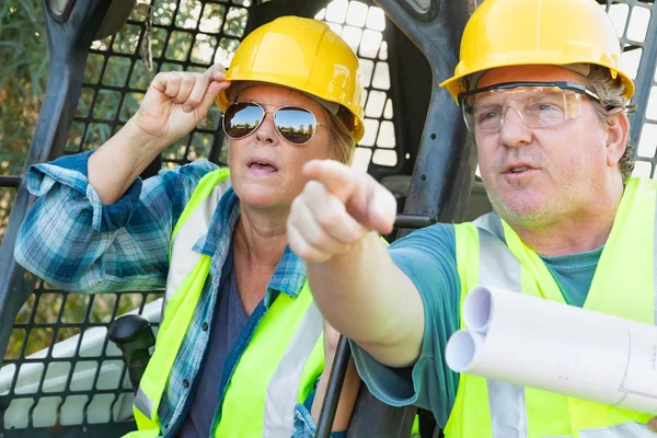 有技术蓝图的男性和女性工人在建筑工地讲话 — 图库照片