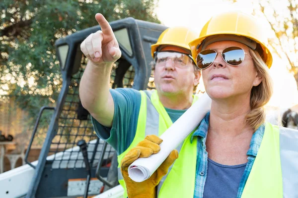 建設現場で話す技術の青写真を持つ男性と女性労働者 — ストック写真