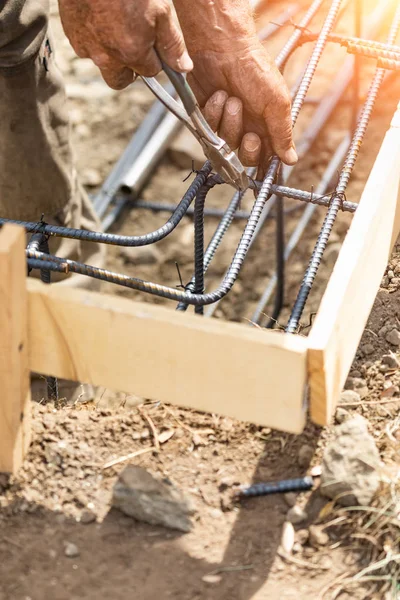 Worker Securing Steel Rebar Framing With Wire Plier Cutter Tool At Construction Site.