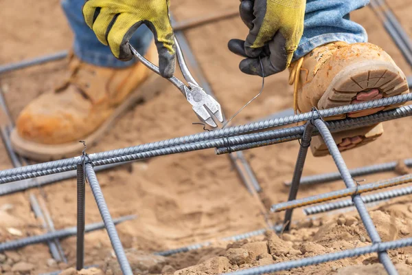 Worker Securing Steel Rebar Framing With Wire Plier Cutter Tool At Construction Site.