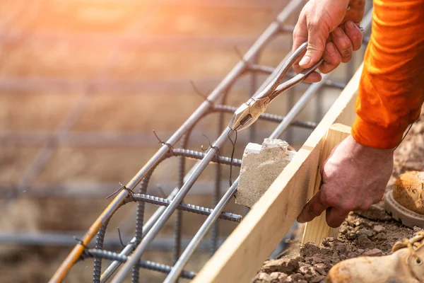 Worker Securing Steel Rebar Framing With Wire Plier Cutter Tool At Construction Site.