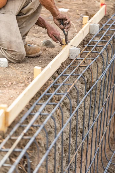 Worker Securing Steel Rebar Framing With Wire Plier Cutter Tool At Construction Site.