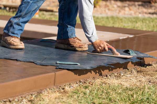 Construction Worker Applying Pressure to Texture Template On Wet Cement
