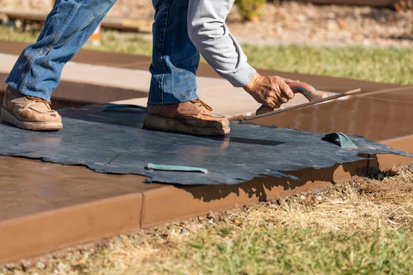 Trabajador de la construcción aplicando presión a la plantilla de textura en cemento húmedo —  Fotos de Stock