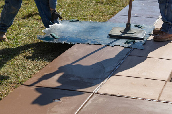 Construction Worker Applying Pressure to Texture Template On Wet Cement